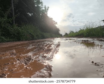 the ground under the setting sun had puddles of water after the rain