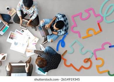 Group of diverse people collaborating on laptops, surrounded by colorful puzzle pieces, symbolizing teamwork and creativity in a modern workspace. Education and learning concept.