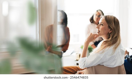 Group of diverse women in a meeting, focused and engaged. Women discussing ideas, collaborating in a bright office. Professional women in meeting. Businesswomen, teamwork, collaboration concept. - Powered by Shutterstock