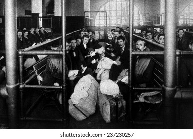 A group of immigrants waiting in a holding pen to be examined by doctors, Ellis Island c.1902.