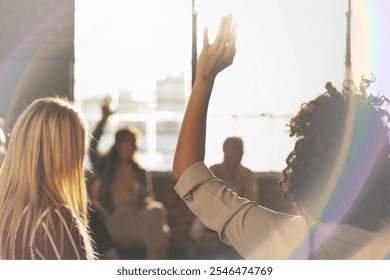 Group meeting with diverse individuals, hands raised, sunlight streaming. Collaborative atmosphere, diverse group, engaging discussion, bright sunlight. Team meeting, connection and discussion.