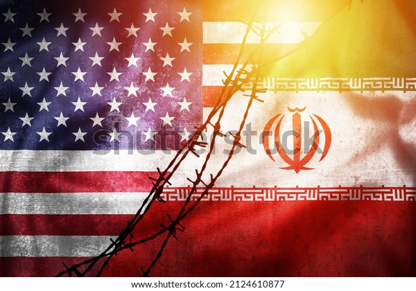 Grunge flags of Iran and USA divided by barb wire sun\
haze illustration, concept of tense relations between Iran and the\
USA