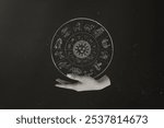 A hand holds a zodiac wheel with astrological symbols on black cosmic background. The zodiac wheel features various zodiac signs. Astrology and zodiac symbols in a cosmic setting.