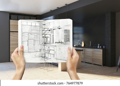 Hands holding notepad with creative kitchen design drawing on blurry interior background. Architecture and engineering concept. 3D Rendering 
