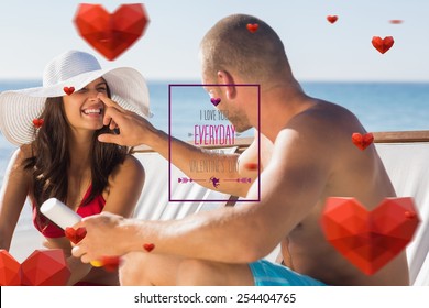 Handsome man applying sun cream on his girlfriends nose against valentines day greeting - Powered by Shutterstock