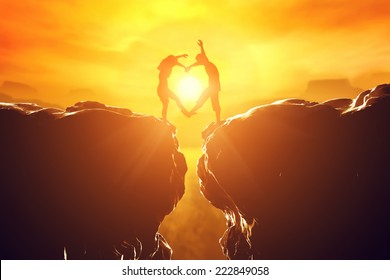 Happy couple making heart shape over precipice between two rocky mountains at sunset. Love unique concept. - Powered by Shutterstock