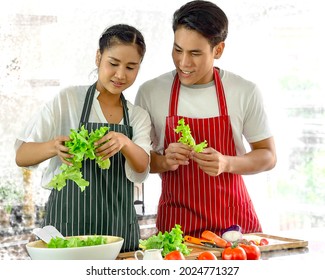 Happy young couple enjoy cooking fresh vegetable salad in kitchen for dinner. Romantic husband and wife stay home together prepare healthy ingredients diet meals as home fun activity at quarantine. - Powered by Shutterstock