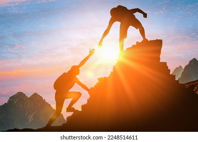 Help and assistance concept. Silhouettes of two people climbing on mountain thanks to mutual assistance and teamwork and partnership. business success and teamwork concept in company - Shutterstock ID 2248514611