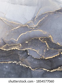 High resolution. Luxury abstract fluid art painting in alcohol ink technique, mixture of black, gray and gold paints.  Imitation of marble stone cut, glowing golden veins. Tender and dreamy design. 