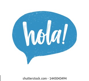 Hola Spanish Greeting Handwritten With White Calligraphic Cursive Font Inside Blue Speech Bubble Or Balloon. Creative Hand Lettering. Modern Illustration For T-shirt, Tee Or Sweatshirt Print