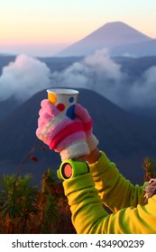 Holding a cup of coffee in front of active volcano. Winter costume. Artistic water colour filter - Palette Knife