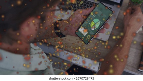 Holding smartphone, man analyzing data at office desk, with laptop, notebook and glowing particles. Technology, analytics, business, digital, innovation, productivity, modern