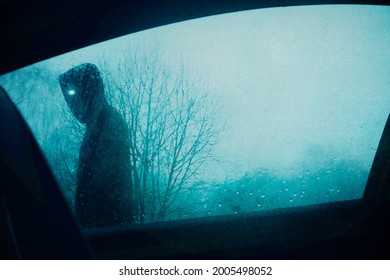 A Horror Concept. Looking Up Through A Car Window At A Scary Supernatural Entity With Glowing Eyes, Walking Past A Car. On A Moody Winters Evening.