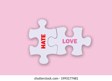 an illustration two white connected puzzles and texts HATE   LOVE pink background