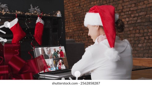 Image of christmas decorations over happy caucasian woman in santa hat on image call with family. christmas with family, tradition and celebration concept digitally generated image. - Powered by Shutterstock