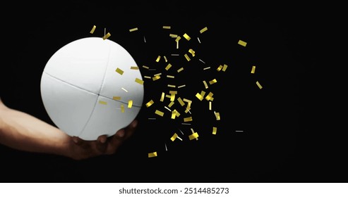 Image of confetti over white rugby ball held by caucasian man's hand on black background. Rugby, sports, competition and celebration concept digitally generated image. - Powered by Shutterstock