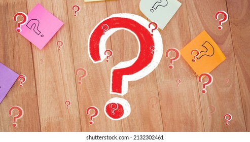 Image of red question marks over multicolour memo notes on wooden background. trivia day, education and learning concept digitally generated image.