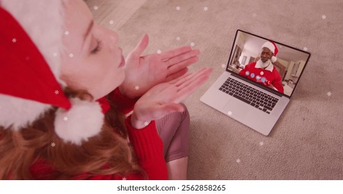 Image of snow falling over happy caucasian woman in santa hat on laptop image call with family. christmas with family, tradition and celebration concept digitally generated image. - Powered by Shutterstock