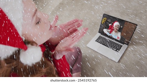 Image of snow falling over smiling woman in santa hat on laptop video call with her family. christmas, tradition and celebration concept digitally generated image. - Powered by Shutterstock