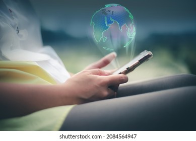Image of a woman holding a smart phone. Technology makes it as comfortable as the whole world is in her hands. Globe sphere of planet earth displayed on a futuristic interface.
