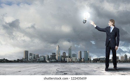 Image of a young businessman holding a shining light bulb - Powered by Shutterstock