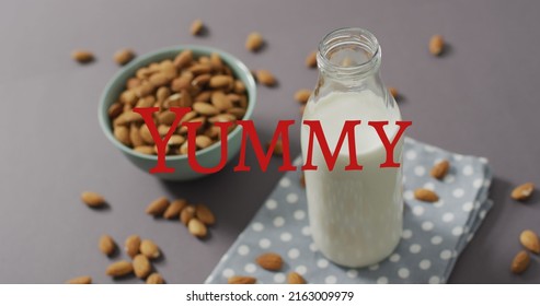 Image Of Yummy Text Over Milk And Nuts. World Milk Day And Celebration Concept Digitally Generated Image.