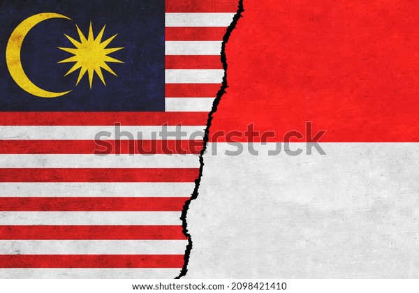 Indonesia and Malaysia painted\
flags on a wall with a crack. Indonesia and Malaysia relations.\
Malaysia and Indonesia flags together. Indonesia vs\
Malaysia
