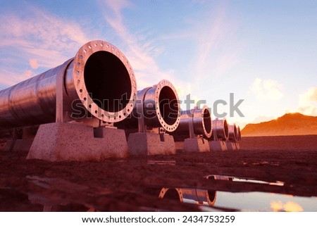 Industrial pipeline segments arrayed for assembly at a construction site, captured against the vivid backdrop of a setting sun reflecting off calm waters.