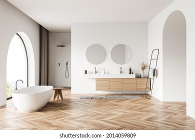 Interior with arches in the bathroom space, having oval white tub, two mirrors and sinks, wooden parquet, pairing with white walls, shower and curtains. Concept of modern design. 3d rendering