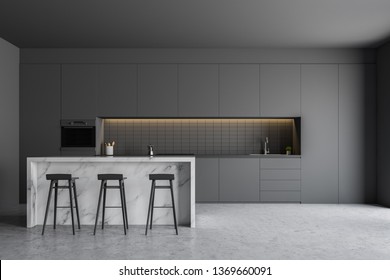 Interior of gray kitchen with concrete floor, gray countertops, built in oven and sink and marble bar with stools. 3d rendering