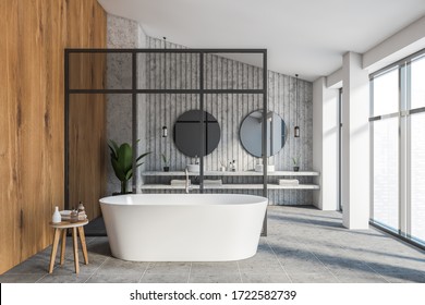 Interior of luxury attic bathroom with white, stone and wooden walls, double sink with two round mirrors, comfortable bathtub near glass wall and panoramic window with blurry cityscape. 3d rendering