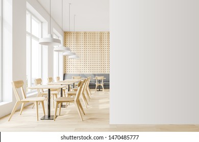 Interior of minimalistic cafe with white and wooden walls, wooden floor, comfortable sofa and wooden tables with chairs. Mock up wall to the right. 3d rendering