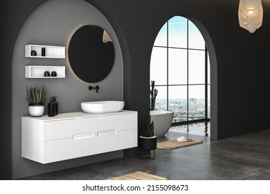 Interior Of Modern Bathroom With Concrete And Black Walls, Concrete Floor And Comfortable White Sink With  Round Mirror, Bathtub, Plant, Pendant Light. Window With City View. 3d Rendering
