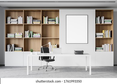 Interior of modern CEO office with white walls, concrete floor, computer table standing near bookcase and vertical mock up poster frame. 3d rendering