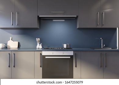 Interior of modern kitchen with blue walls, gray countertops with built in cooker and sink and grey cupboards above them. 3d rendering