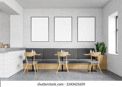 Interior Of Modern Loft Restaurant With White Brick Walls, Concrete Floor, Comfortable Grey Sofa With Square Wooden Tables And Chairs And Mock Up Poster Gallery. 3d Rendering