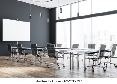 Interior Of Modern Office Meeting Room With Grey Walls, Wooden Floor And Glass Conference Table With Black Chairs And Mock Up Projection Screen. 3d Rendering