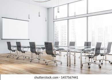 Interior Of Modern Office Meeting Room With White Walls, Wooden Floor And Glass Conference Table With Black Chairs And Mock Up Projection Screen. 3d Rendering