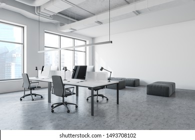 Interior Of Modern Open Space Office In Industrial Style With White Walls, Concrete Floor, Long Computer Tables With Chairs And Lounge Area With Gray Poufs. 3d Rendering