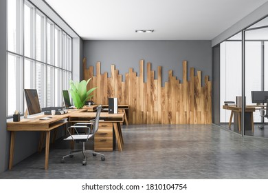 Interior of modern open space office with gray and wooden walls, concrete floor and wooden computer tables. 3d rendering