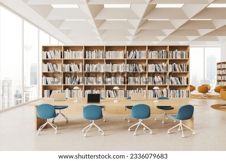 Interior of modern public library reading room with white walls, panoramic windows, rows of bookcases and long wooden table with laptops and blue chairs. 3d rendering