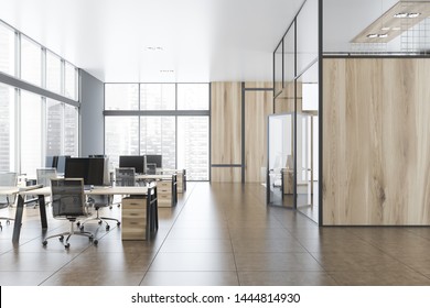 Interior of stylish open space office with gray and wooden walls, tiled floor, panoramic windows with cityscape and rows of gray and wooden computer desks. Hall with open door. 3d rendering