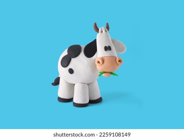 Little Cow handmade with plasticine on a blue background. 3D artwork. Cow figure eating grass handmade with plasticine clay, farm animal. - Shutterstock ID 2259108149