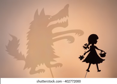 Little Red Riding Hood shadow puppet and the Big Bad Wolf's shade with the soft glowing screen of shadow theater in the background.
