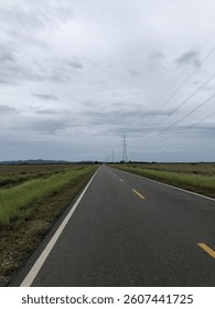 Long empty road under cloudy sky