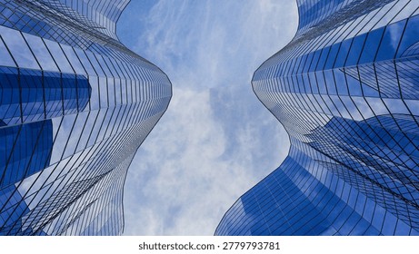 Low angle view of 3D modern blue glass skyscrapers with curved facades under a cloudy blue sky