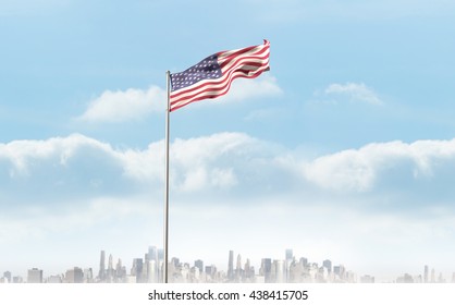 Low angle view of American flag against city on the horizon