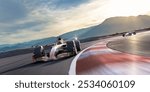 Low angle view of two generic racing cars moving at high speed around a bend at high speed of a racetrack close to mountains under a late afternoon sky.