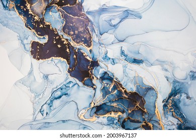 Luxury abstract fluid art painting in alcohol ink technique, mixture of dark blue, gray and gold paints. Imitation of marble stone cut, glowing golden veins. Tender and dreamy design.