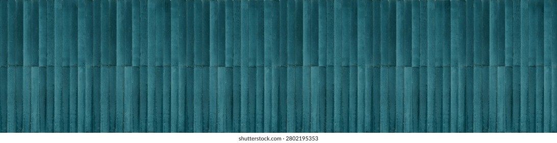 A luxury wall surface featuring glossy teal glazed ceramic tiles arranged in a vertical stacked pattern, showing natural color gradations and emerald undertones.